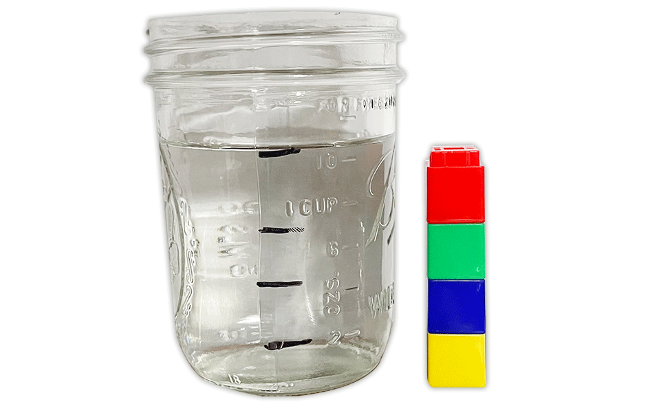 A jar filled with water and a stack of colored cubes beside it